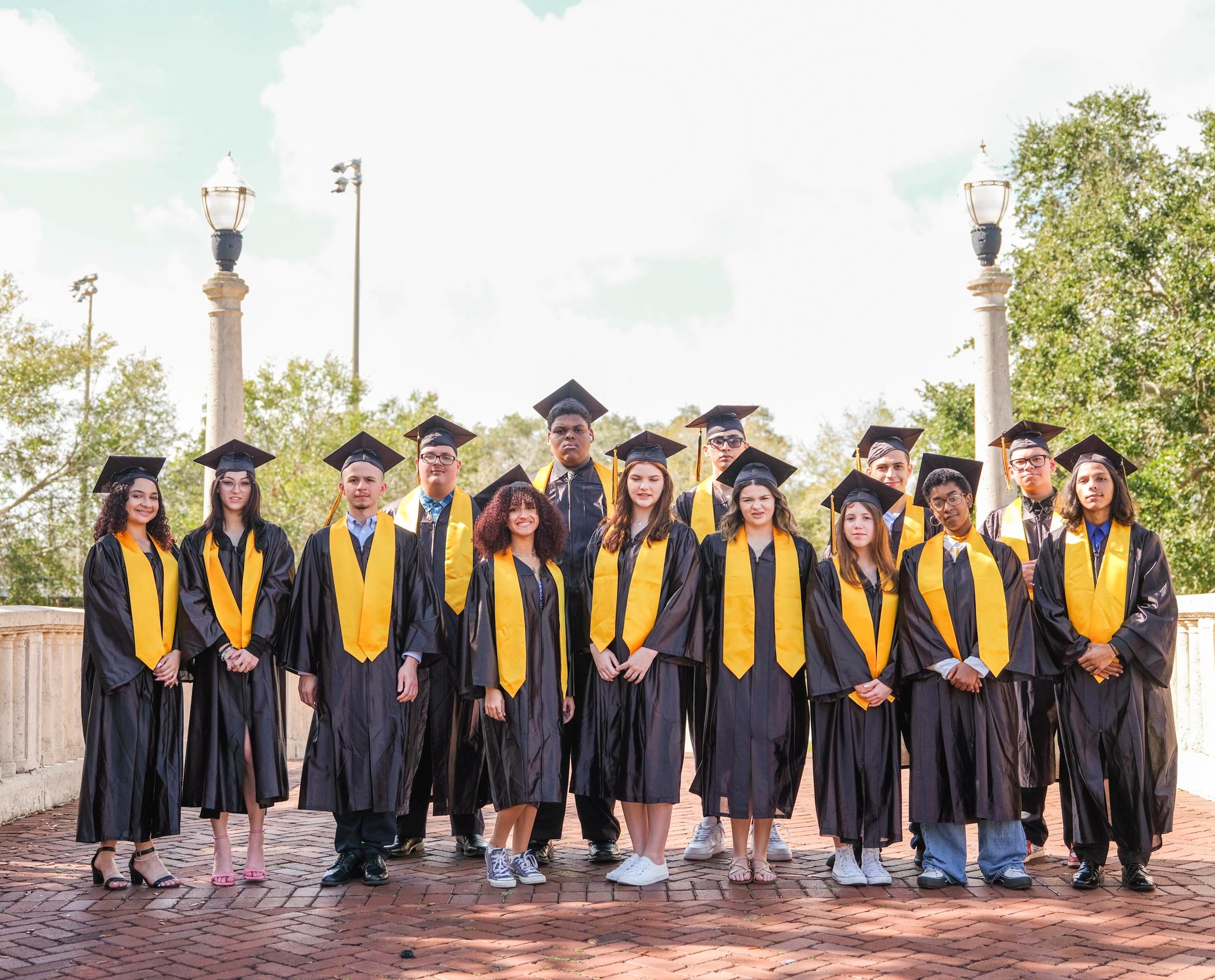 14 UEC graduates pose for a group photo in their regalia. 